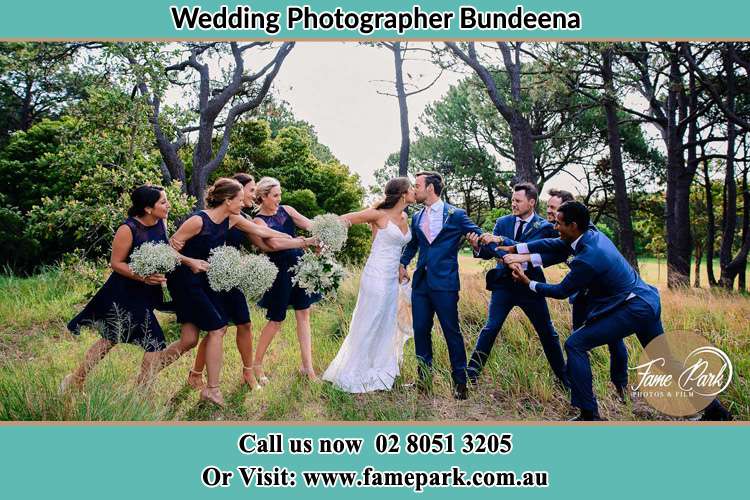 Photo of the Bride and the Groom kissing while teasing by the entourage Bundeena NSW 2230