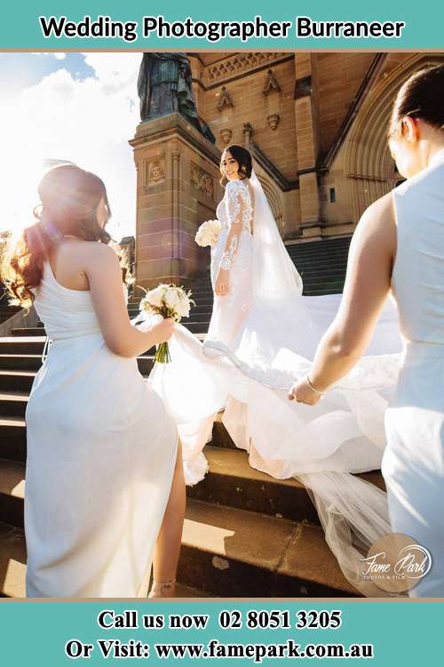 Photo of the Bride smiling on the bridesmaid holding the tail of her wedding gown at the front of the church Burraneer NSW 2230