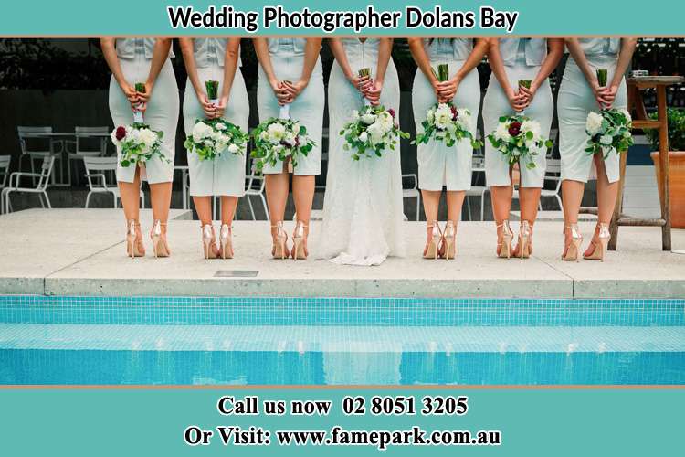 Behind photo of the Bride and the bridesmaids holding flowers near the pool Dolans Bay NSW 2229