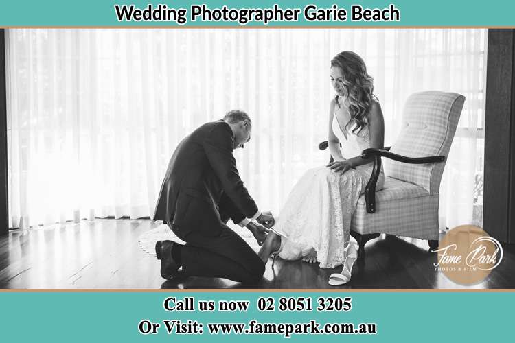 The Bride is being helped by the Groom trying to put on her shoes Garie Beach NSW 2233