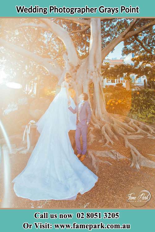 Photo of the Bride and the Groom looking each other besides the tree Grays Point NSW 2232