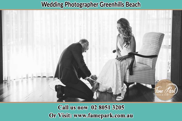 The Bride is being helped by the Groom trying to put on her shoes Greenhills Beach NSW 2230