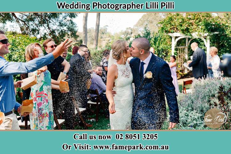 Photo of the Bride and the Groom kissing while showering rice by the visitors Lilli Pilli NSW 2229