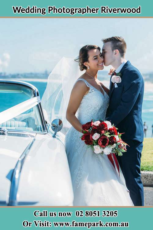 Photo of the Groom kiss the Bride besides the bridal car Riverwood NSW 2210