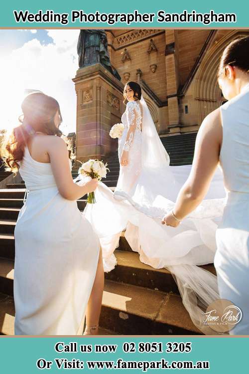 Photo of the Bride smiling on the bridesmaid holding the tail of her wedding gown at the front of the church Sandringham NSW 2219