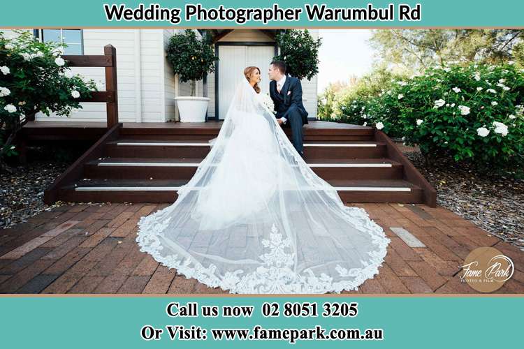 Photo of the Bride and the Groom looking each other while sitting at the staircase Warumbul Rd NSW 2233